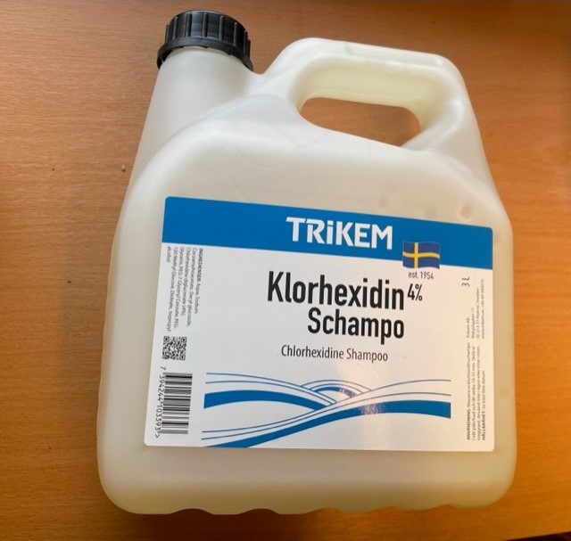 En vit behållare med TRIKEM Klorhexidinschampo 3000ml på en träyta.