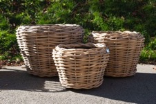 Korgkruka Rattan rund - Mellan visas tom på trottoar med grönska i bakgrunden.