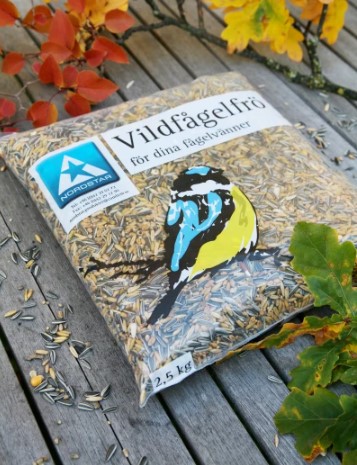 En 2,5 kg påse viltfågelfröblandning med en fågelbild på en träyta och höstlöv.