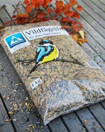 Vildfågelfröblandning 4kg med en blå och gul fågelillustration på ett träbord.
