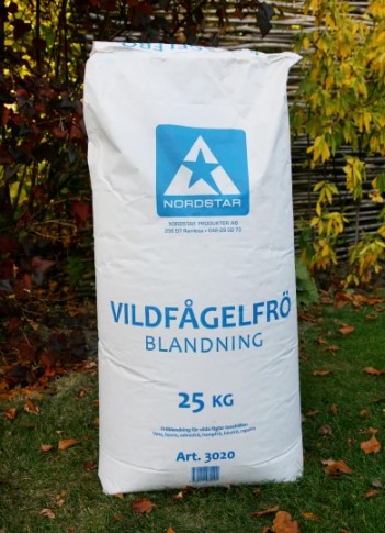 En 25 kg säck med vildfågelblandning för vilda fåglar står på gräs.