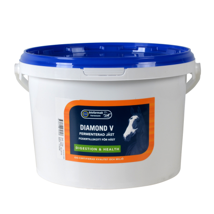 Vit plasthink med blått lock, märkt Diamond V hästtillskott för matsmältning och hälsa.