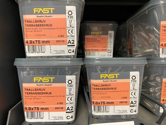 Fyra lådor TRALLSKRUV 4,8x75 A2 (150 st) visas på en butikshylla.