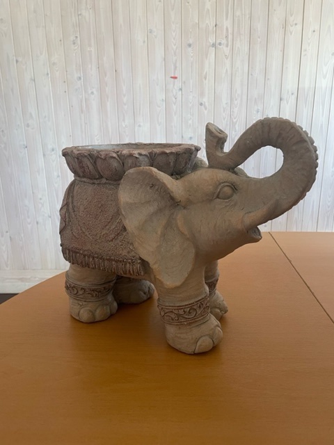 Dekorativ elefantplantering med upphöjd snabel, placerad på ett träbord.