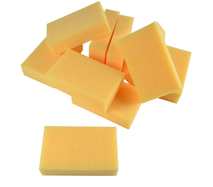 En grupp rektangulära gula rengöringssvampar mot en vit bakgrund.