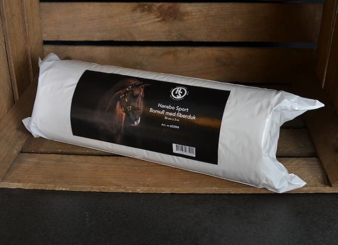 Ett vitt Bomull med fiberduk 30cmx3m paket med en hästbild vilar på en trälåda.