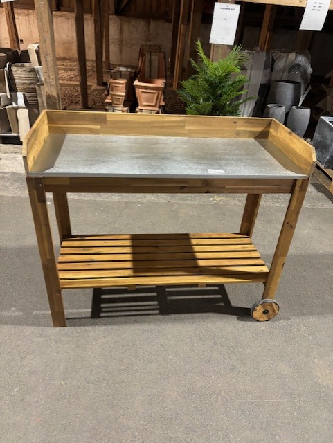 Planteringsbord med hjul: trävagn med metalltopp och hylla, två hjul, för inomhusbruk.