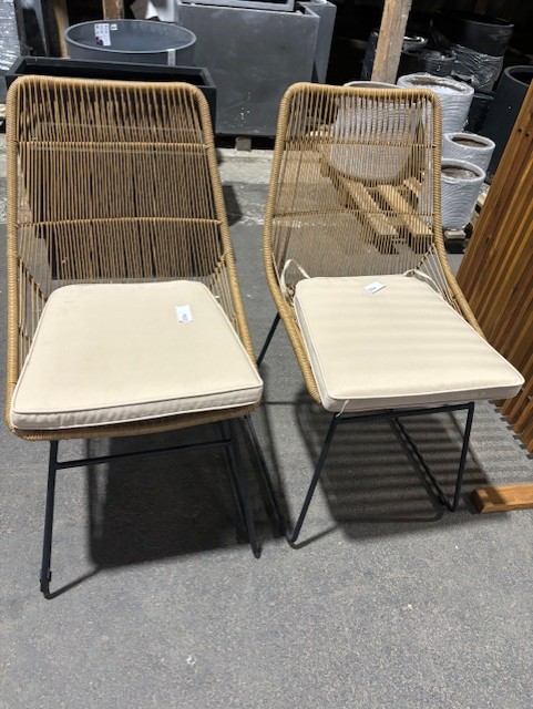 Två Stol med dyna 653 stolar med beige dynor och svarta ben på ett betonggolv.