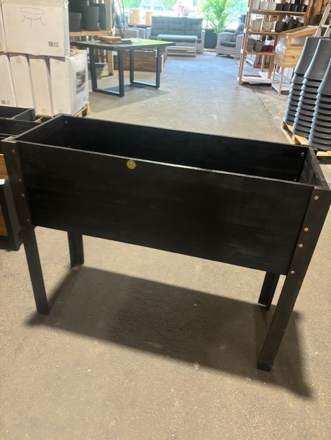 Odlingslåda 108x40x84 svart träplanteringslåda med ben står i en butiksgång.
