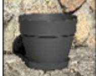 En Plastkruka svart 47cm sitter på en stenyta med klippor i bakgrunden.