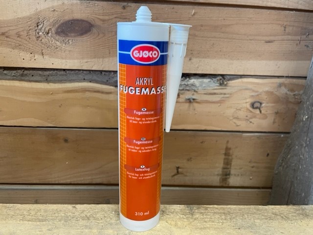 En tub Akryl fogmassa vit 310ml fogmassa på trä med en trävägg i bakgrunden.