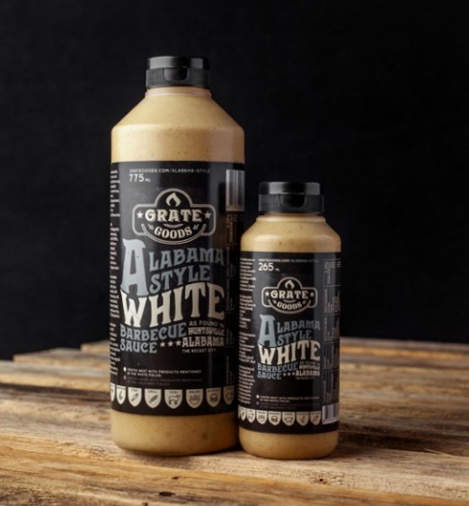 Två flaskor Alabama White Barbecue Sauce på en rustik träyta.