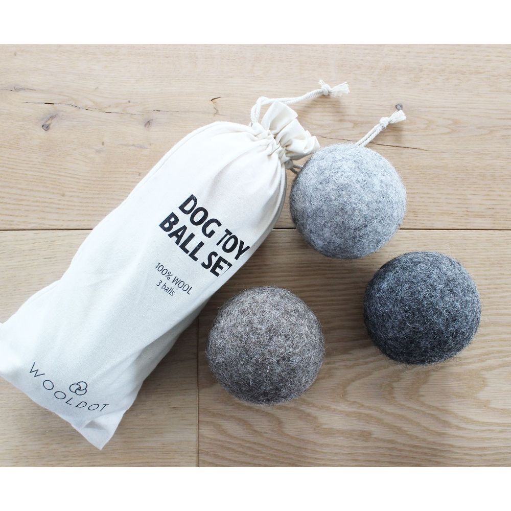 Three Wooldot Toy Ball set 3st bredvid en märkt påse på en träyta.
