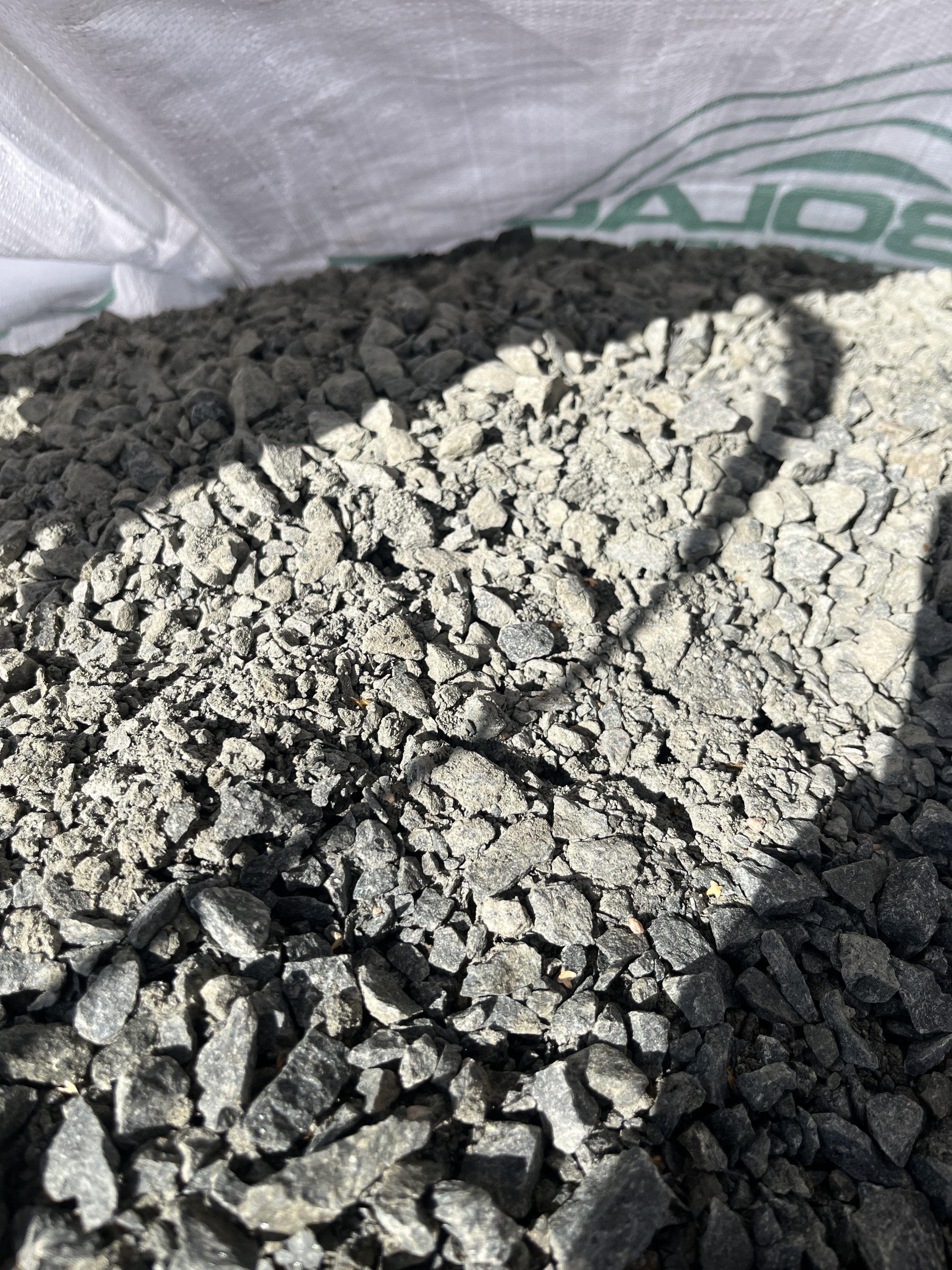 Närbild på Bigbag Bergkross svart 0-16, ca600kg, grå grusstenar i en vit tygpåse.