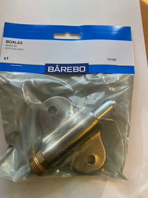 En förpackad BS LÅS utan bleck låskomponent i metall på en vit yta.