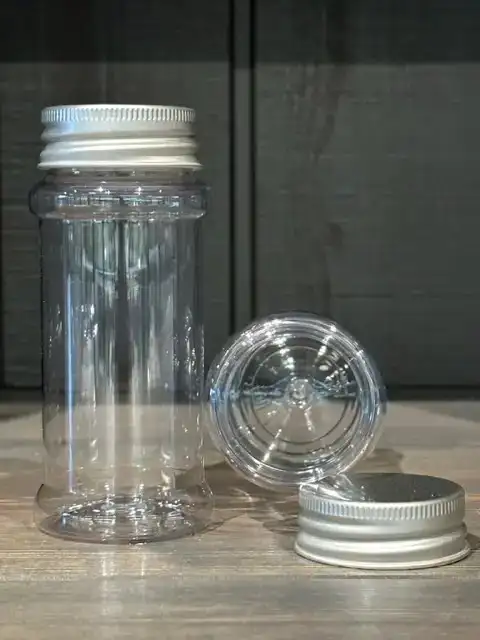 KRYDDBURK 100 ml burk i PET-plast med aluminiumlock; extra lock och burk bredvid.