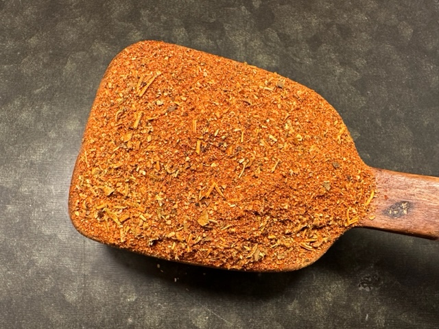 En träspatel toppad med Cajunkrydda för kött, en rödbrun kryddblandning.