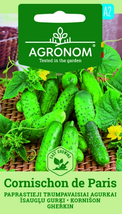 Färsk grön gurka Cornichon De Paris på korg och bord med etikett på fröförpackning.