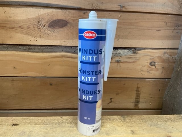 Fönsterkitt Natur 310ml patron på träyta med en trävägg i bakgrunden.