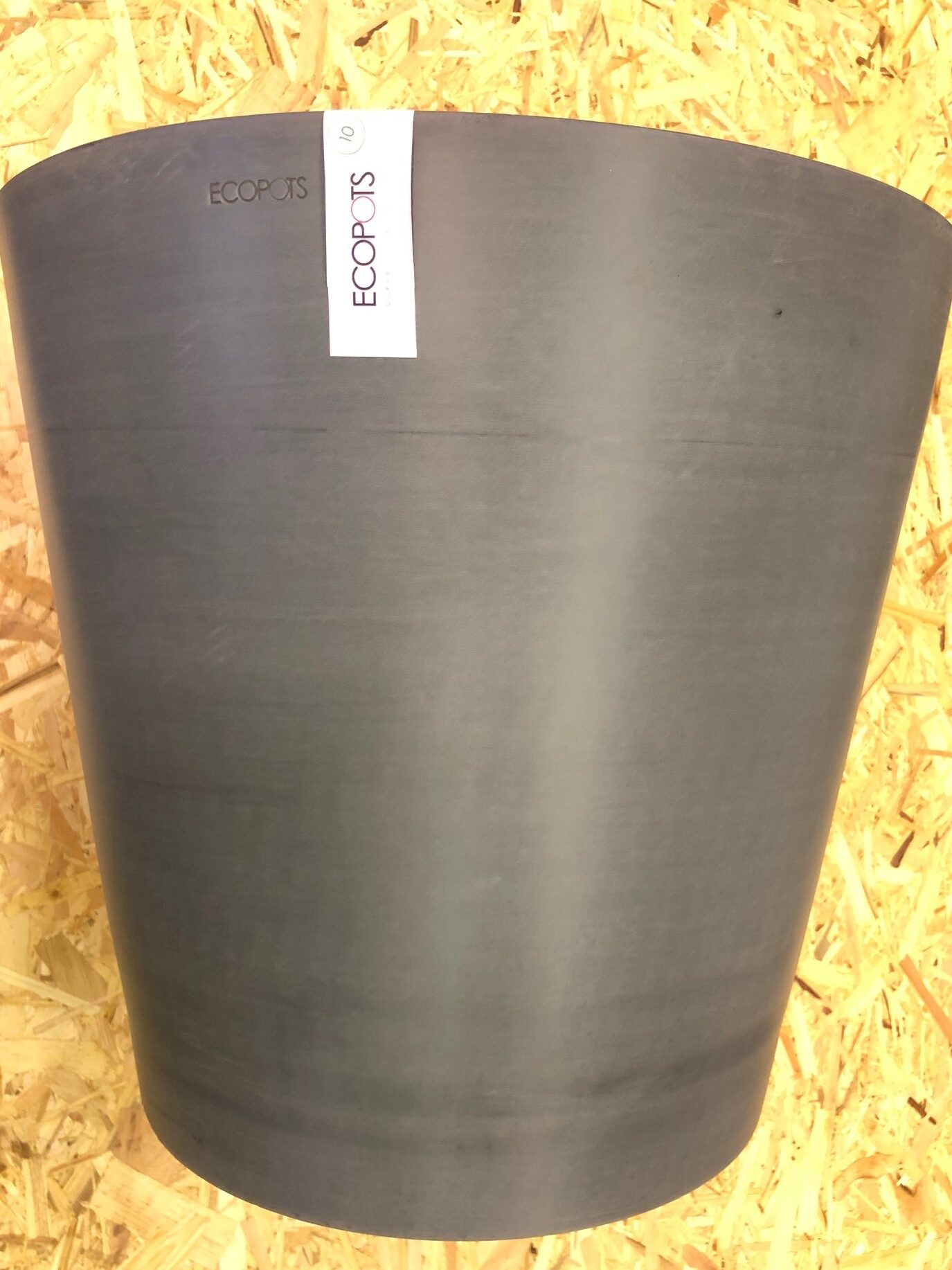 En stor grå ECOPOTS kruka mot en bakgrund av träflis.