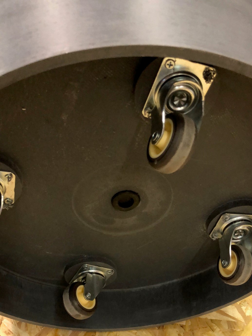 Närbild av undersidan av ett runt föremål med fyra små länkhjul på.