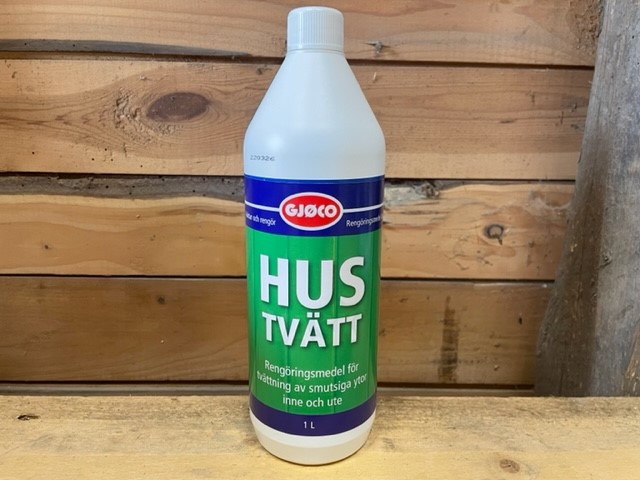 En flaska med Hustvätt 1LITER rengöringsmedel på en träyta med träbakgrund.