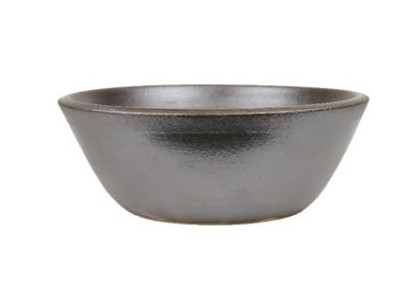 En enkel, rund KRUKA ILLA SVART-skål i mörkgrå keramik mot en vit bakgrund.