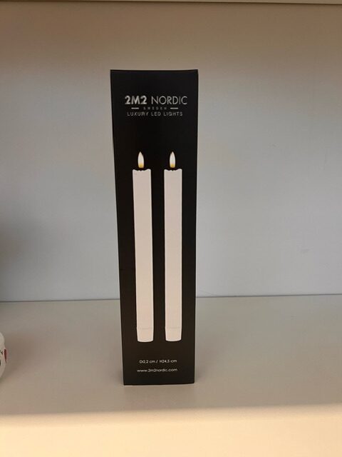 Låda med TABLE CANDLE 2-P WAX H24,5 med bild av två vita LED-ljus på framsidan.