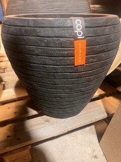 En stor Kruka capi antracit kruka står på en träpall.