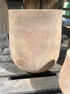 Keramikkrukan KRUKA ANTIK TERRA S/3 - S står på en träpall i solljus.