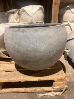 KRUKA FIBER GRÅ BOLL S/3 - S planteringsmaskin står på en pall i ett lager.