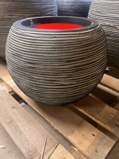 KRUKA CAPI RIB ANTRACIT D40, rund ribbad grå planteringslåda, på träpall.