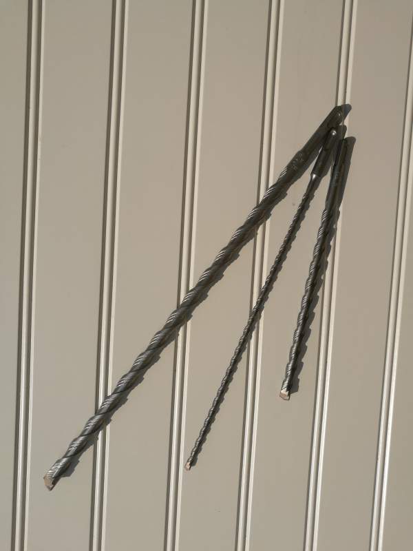 En Wemax Hammarborr 8,0x160mm murarborr lutar sig mot en beige, räfflad vägg.