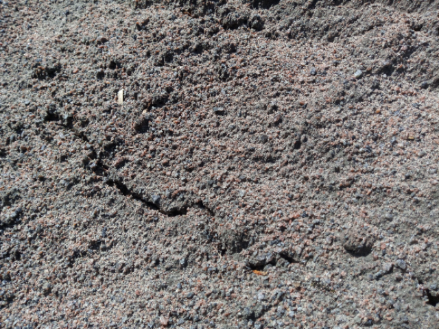 Närbild av Bigbag Stenmjöl 0-2, 600kg som visar torr, sprucken jord med små stenar.