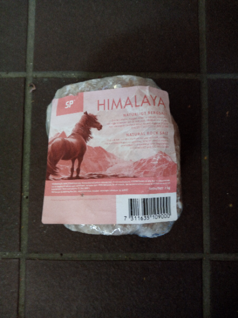 En förpackning Himalya saltsten med en hästbild på etiketten, på en kaklad yta.