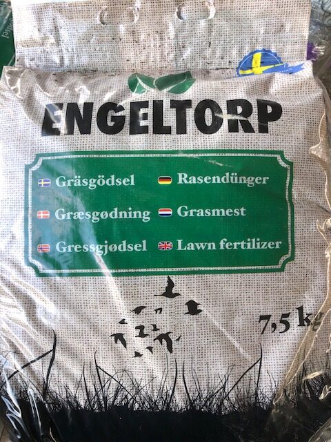 Påse märkt "Gräsgödsel 7,5 kg NPK 21-4-7" för gräsmattor, med information på flera språk.