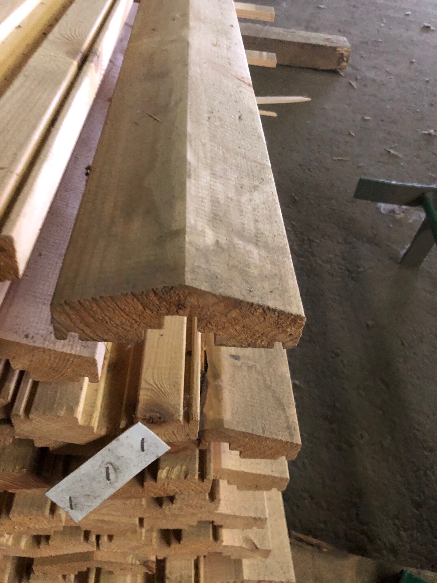 Stapel med Överliggare 2700 brädor med vinklade kanter i en verkstad eller på ett virkesområde.