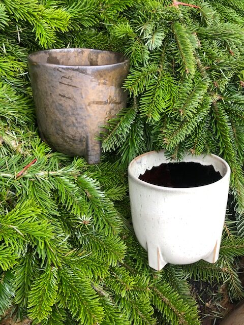 En guldfärgad kruka, Kruka guldfärgad D17,5, placerad bland gröna tallgrenar.