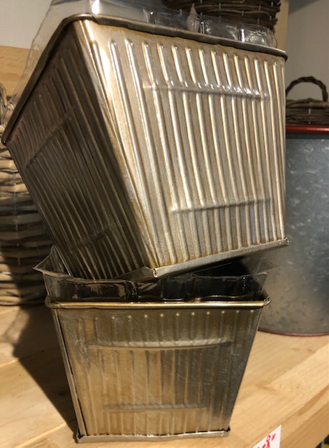 Två staplade Zinkkruka guld silvrig - Små burkar med räfflade sidor på en hylla av trä.