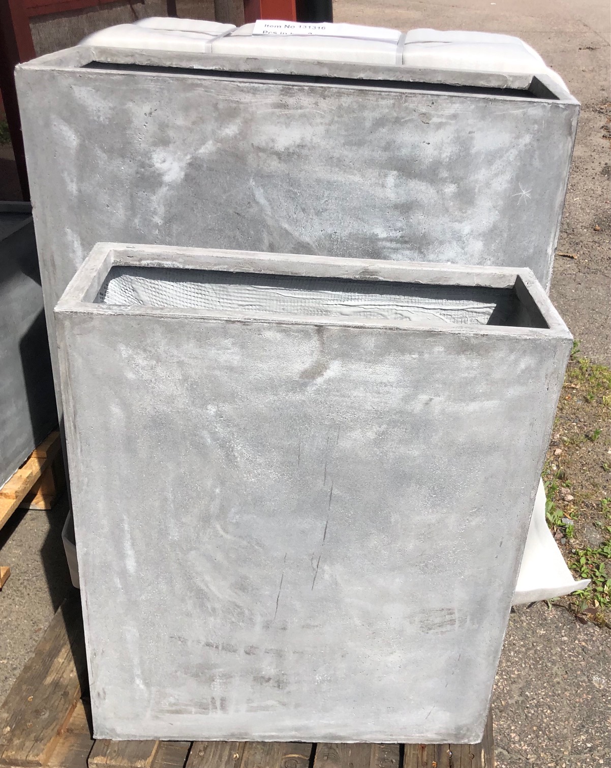 Två stora Kruka fiber höga rektangulära planteringskärl placerade utomhus på en träpall.