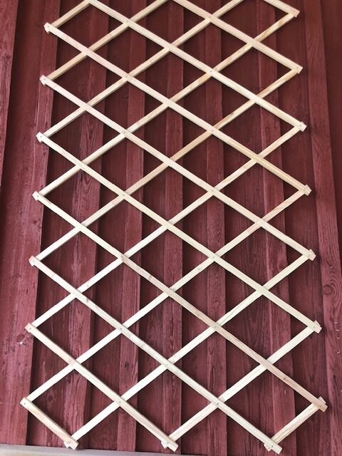 Spalje i trä monterad på en röd trävägg.