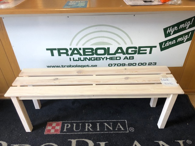 Träbänk i ljust trä framför en butiksdisk med skylten TRÄBOLAGET.