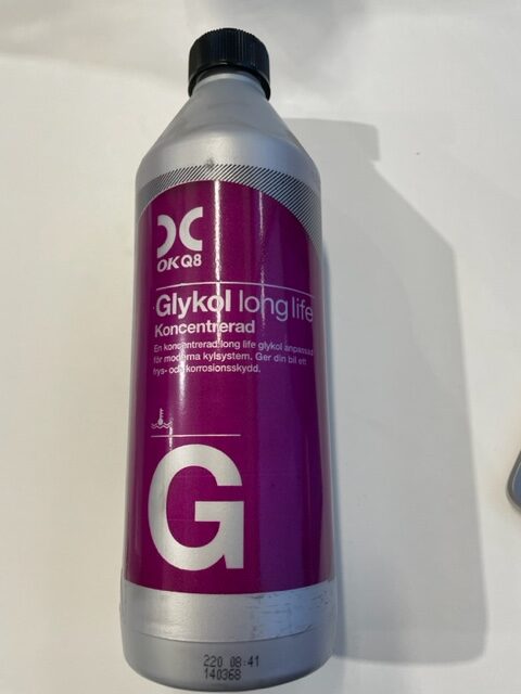 En silverfärgad 1L flaska märkt Glykol longlife koncentrerad med en lila etikett.