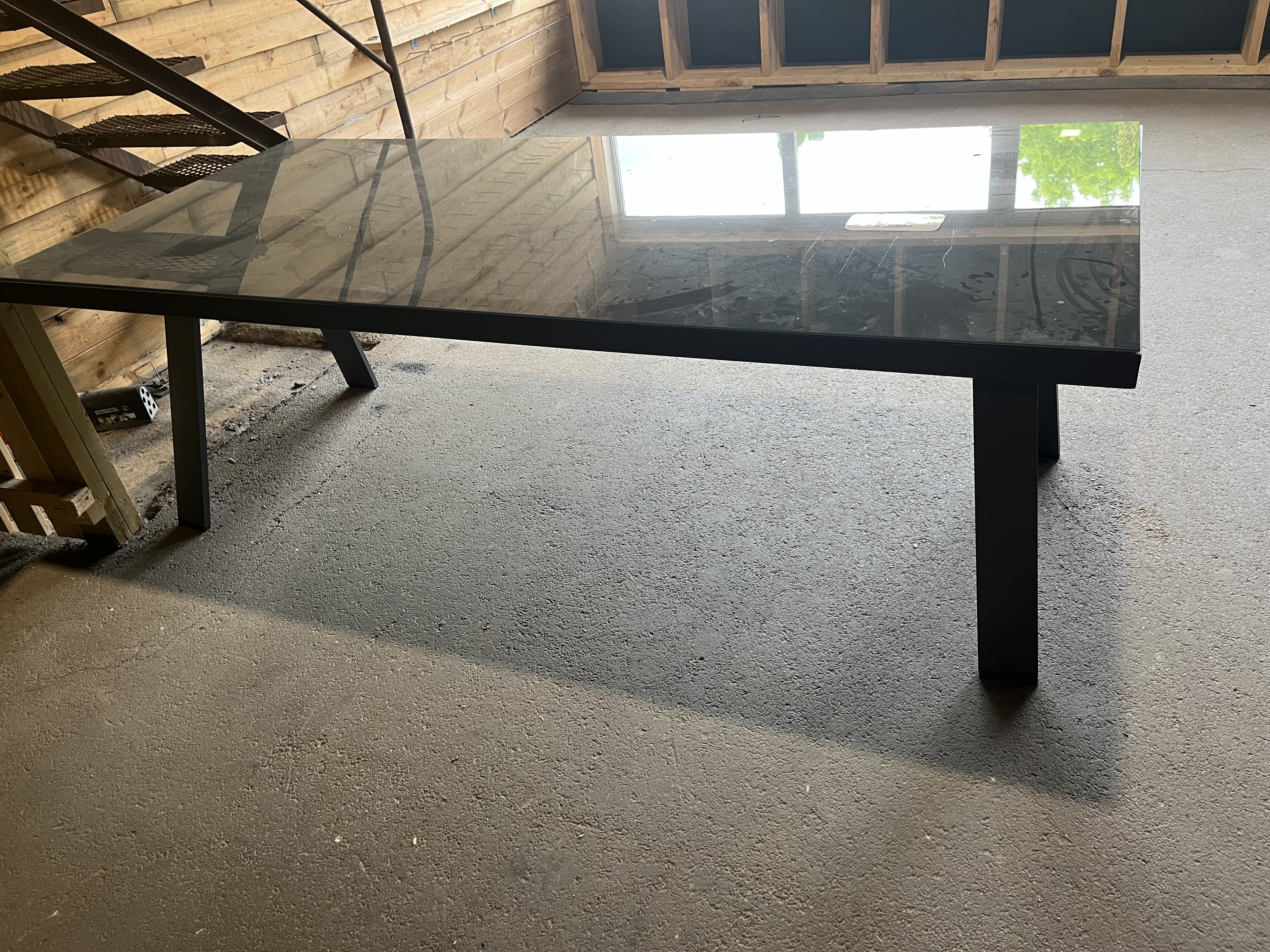 Ett Metallbord med glasskiva och svarta ben i ett delvis färdigställt rum.
