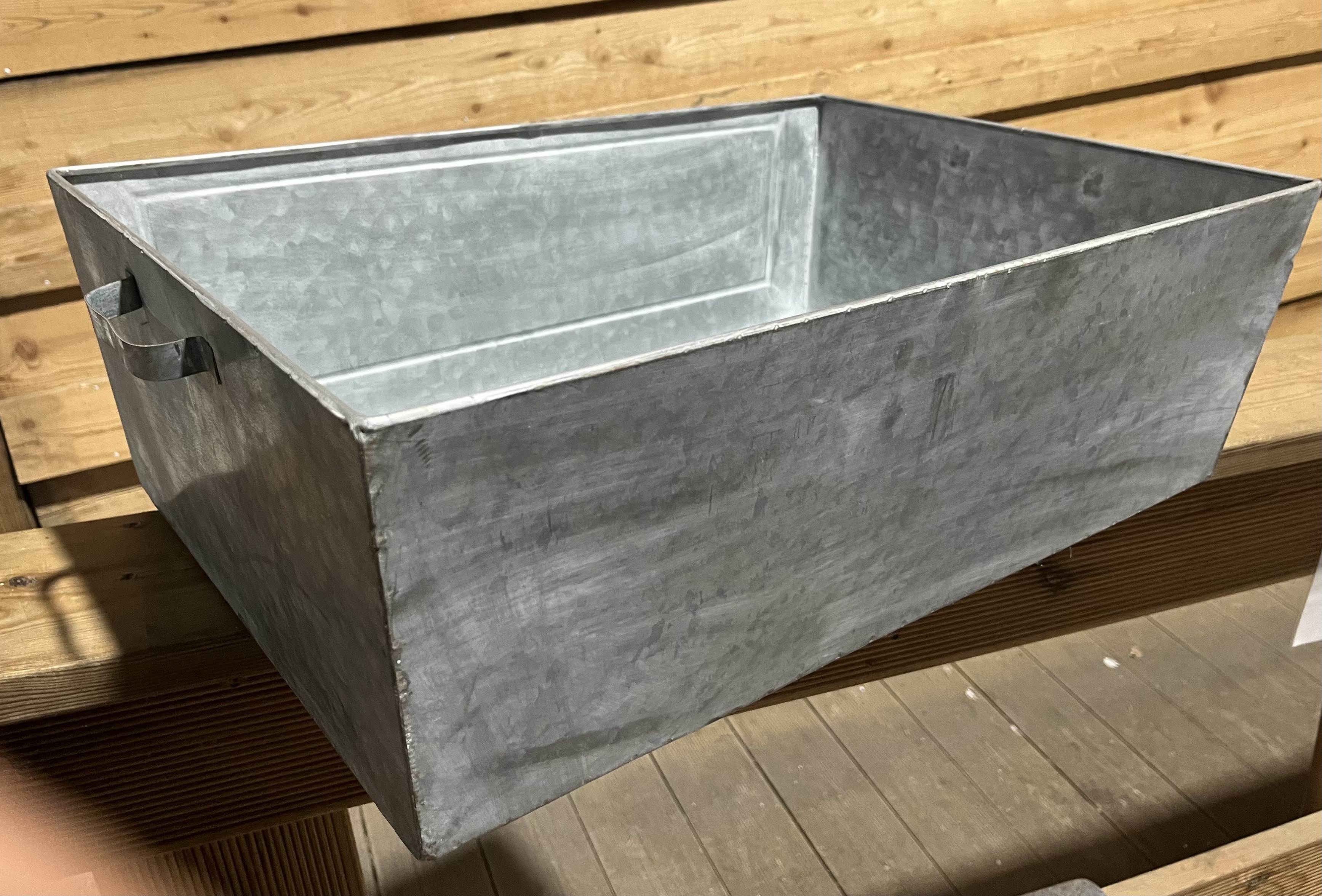 Zinkkruka (ej täta) 57x39x19 med handtag på en träyta.