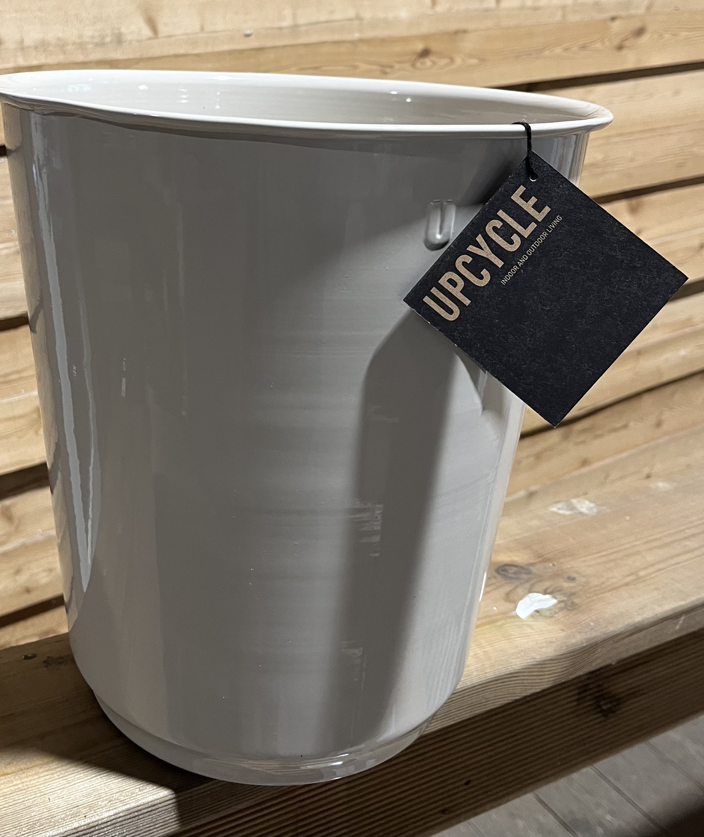 Ny ria 36x36x38 krämbehållare med Upcycle-tagg på träyta, trävägg bakom.