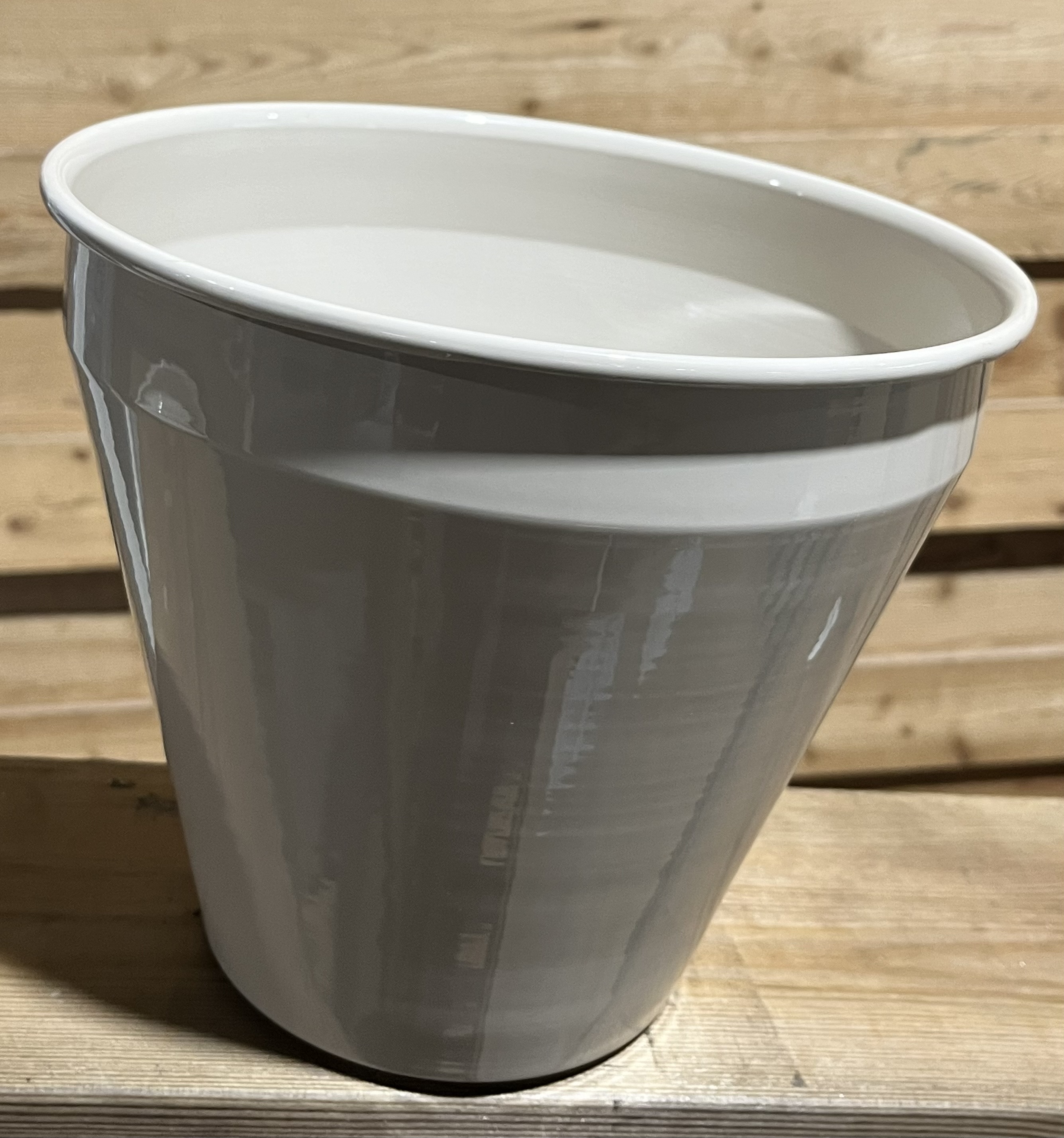 Konical 22,5x22,5x20 gräddkruka står på trä med en bakgrund av trä.