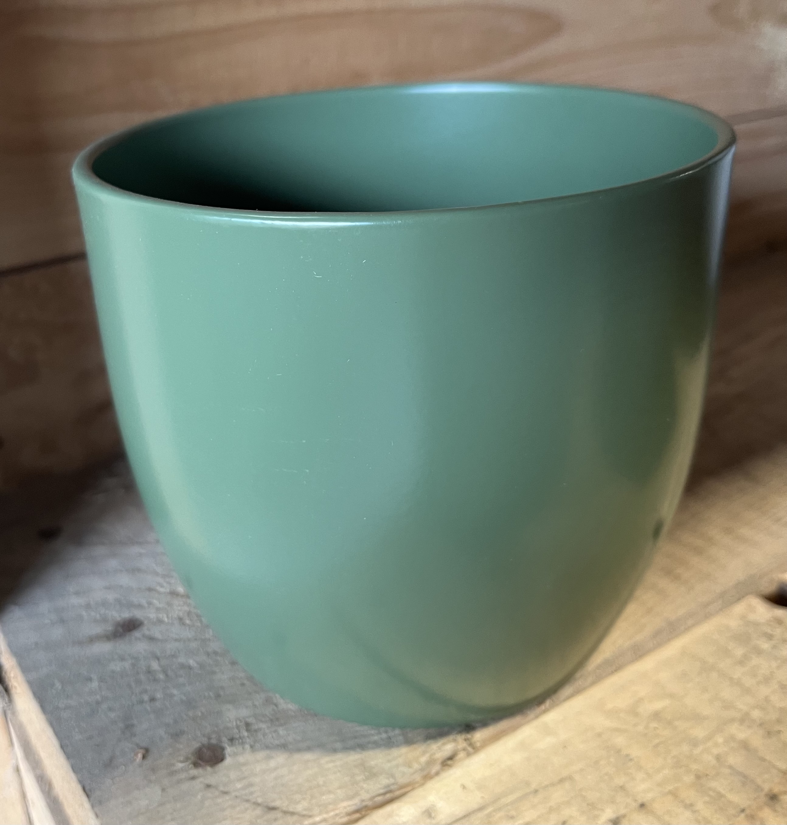 En matt blomkruka från Basel Moosgrün på en träyta.