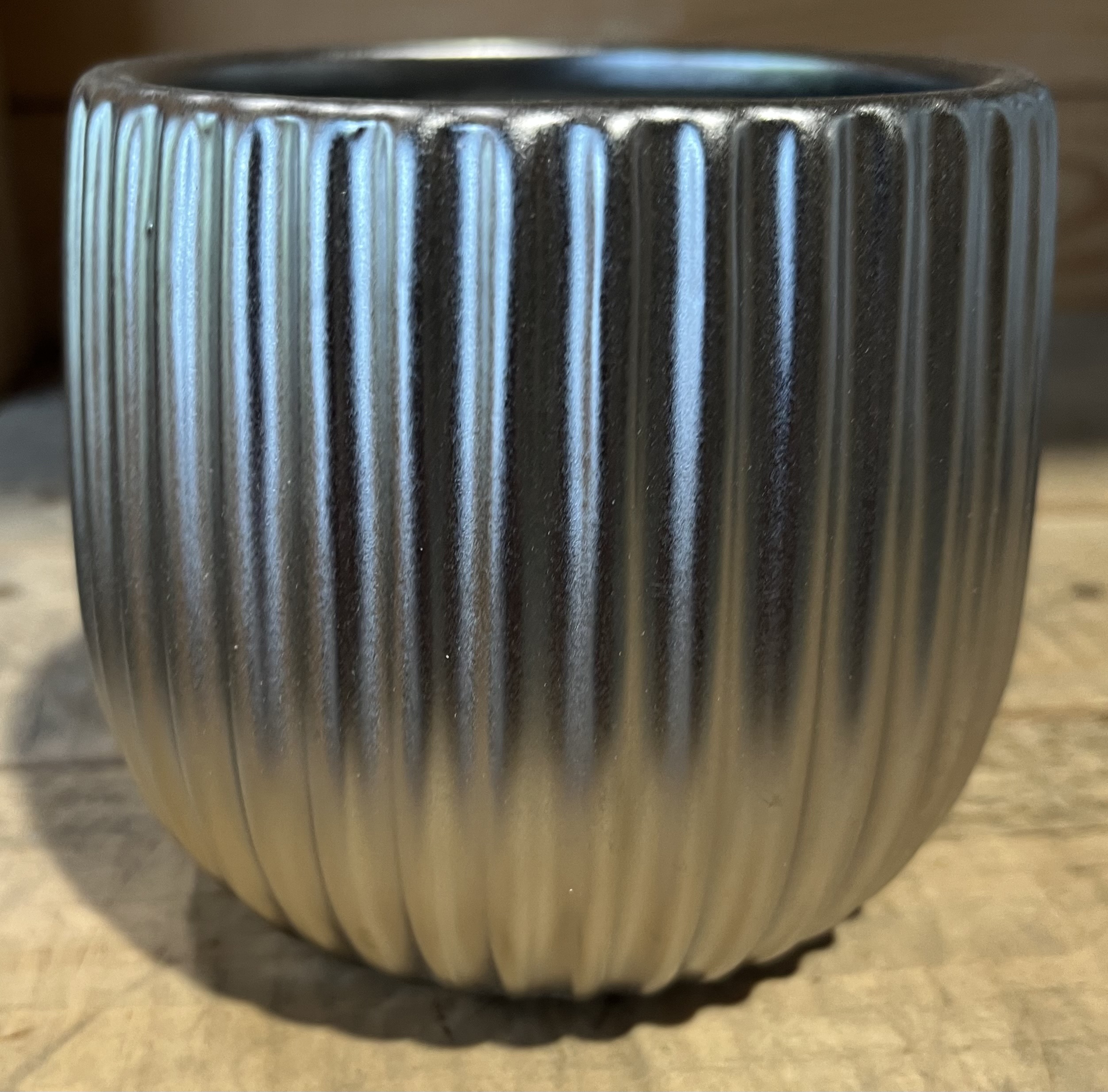 Kruka silver D12, en räfflad metallkruka, står på en träyta.