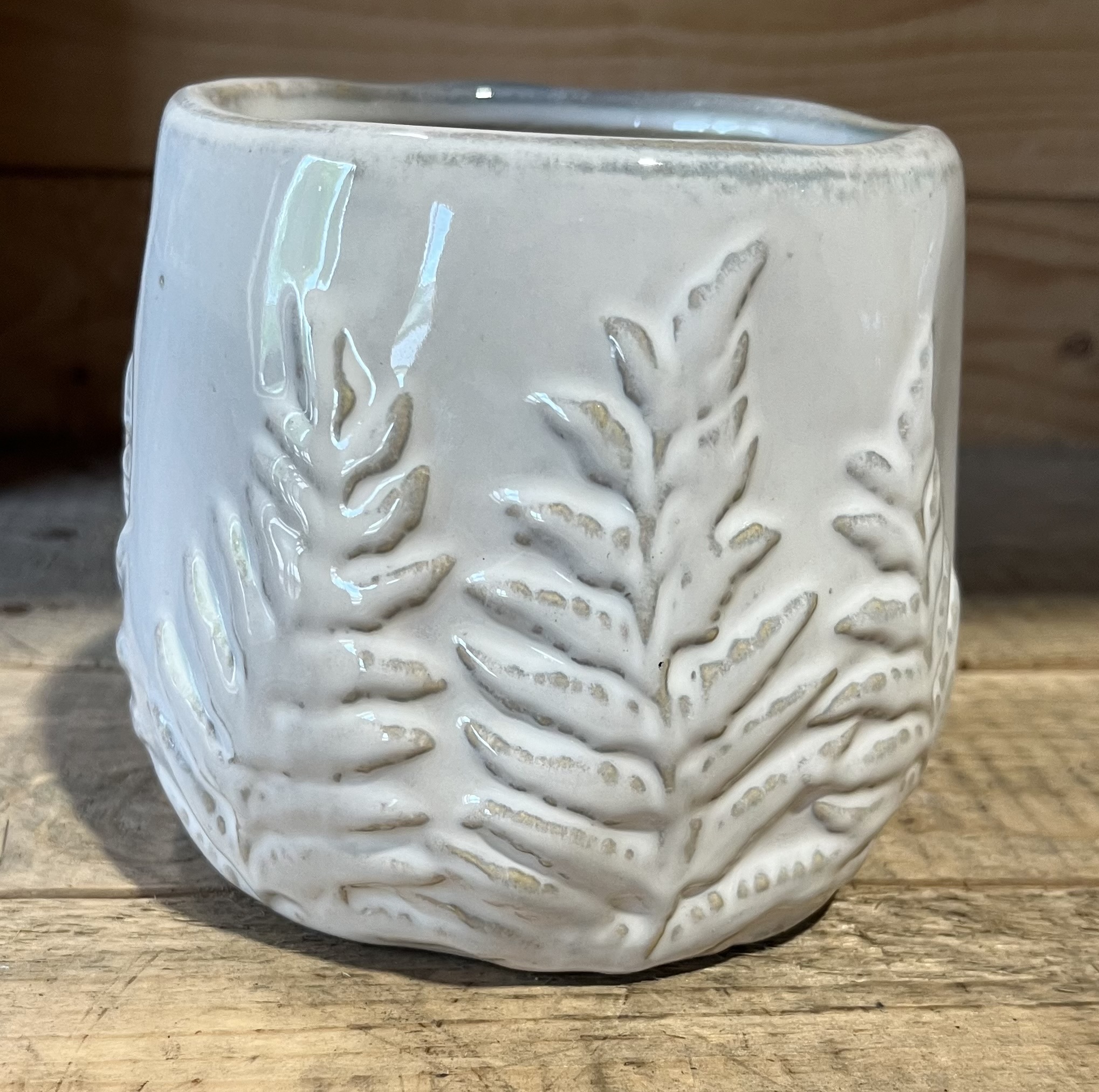 Keramikkruka vit gran D15,5 med ett upphöjt bladmönster på en träyta.